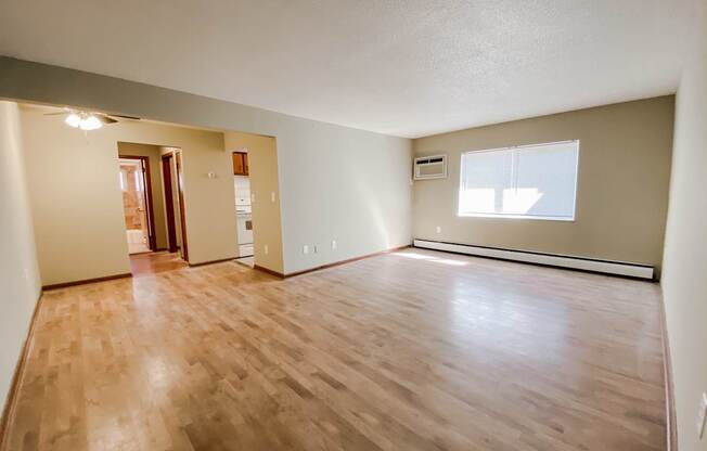 an empty living room with wood floors and a window