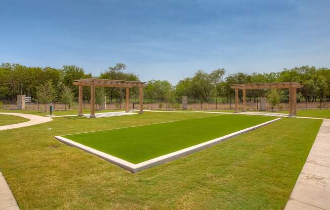 a grassy area with two pergolas in the background
