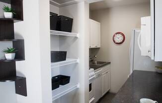 a kitchen with white cabinets and a clock on the wall