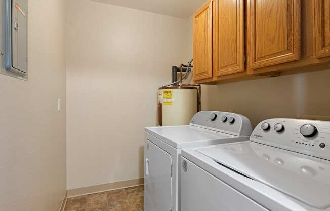 the laundry room has a washer and dryer and wood cabinets