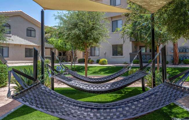 two hammocks on a lawn in front of an apartment building