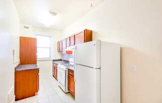 kitchen with tile flooring, white appliances and oak cabinetry at chatham courts apartments in washington dc