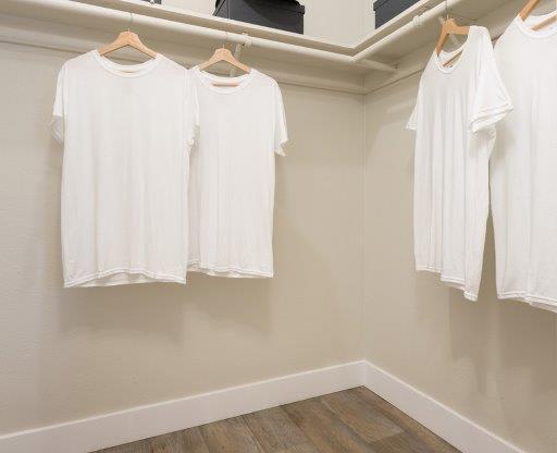 four white shirts hanging on a rack in a room