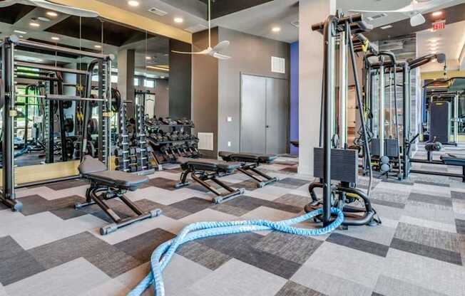 A gym with a variety of equipment including treadmills, weights, and exercise machines.