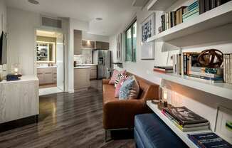 A living room with a brown leather couch and a bookshelf filled with books.