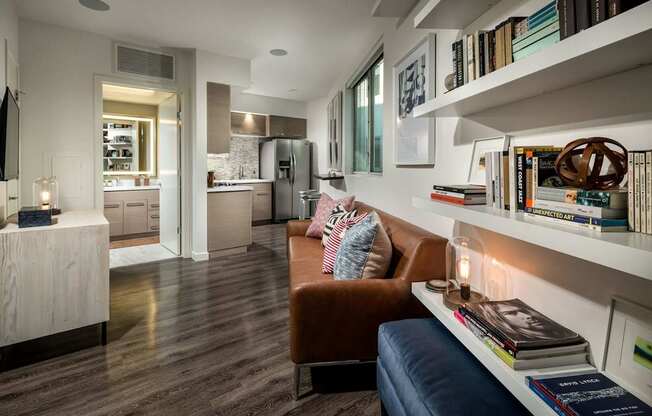 A living room with a brown leather couch and a bookshelf filled with books.