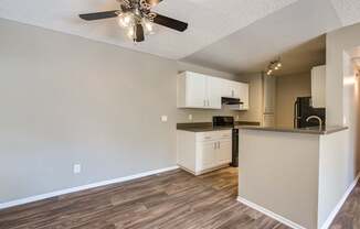 A kitchen with a ceiling fan and wooden floors.