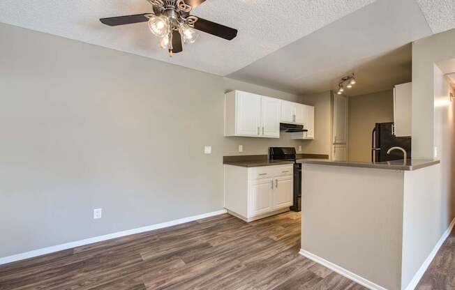 A kitchen with a ceiling fan and wooden floors.