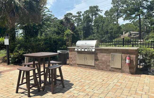 A patio with a table and chairs and a grill.