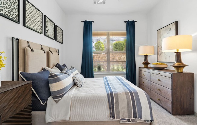 A bedroom with a large bed, two lamps, and a window with curtains.