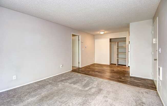 an empty living room with a door to a closet and a hard wood floor