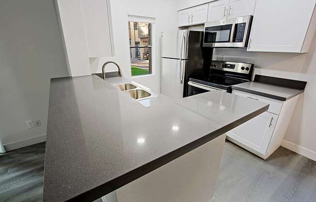 a kitchen with white cabinets and a black counter top