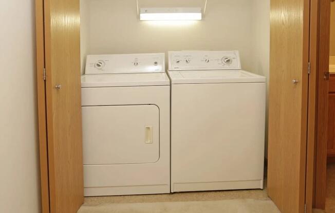 A pair of white front loading washing machines in a small laundry room.