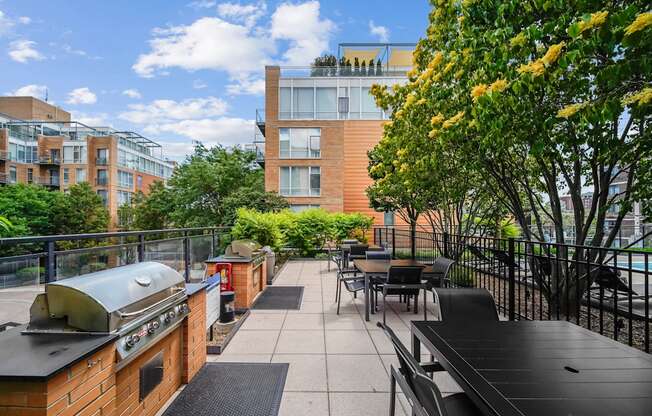A patio with a grill and chairs overlooks a courtyard.