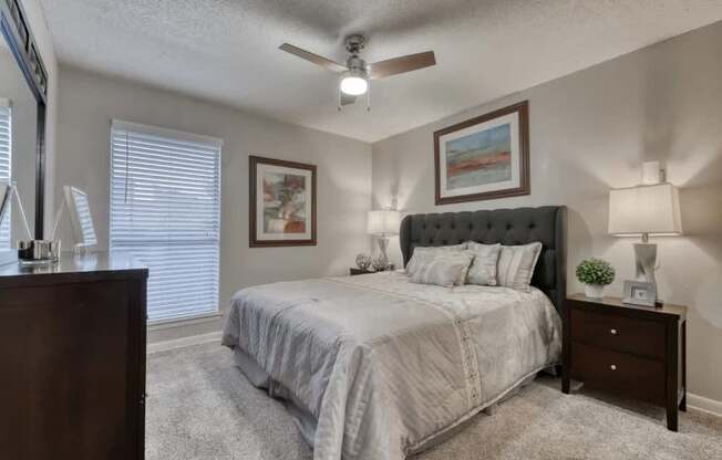 A bedroom with a bed, nightstand, and a painting on the wall.