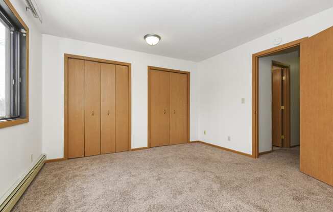 an empty living room with three doors and carpeting. Anoka, MN Dellwood Estates