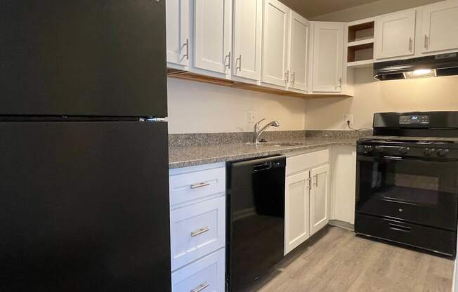 a kitchen with white cabinets and black appliances at Barracks West in Charlottesville, VA