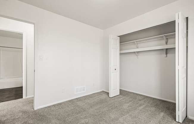 A white bedroom with a closet and carpeted floor at Tanglewood Apartments, Oak Creek, WI