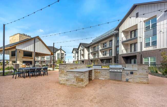 A courtyard with a stone wall and a grill in the middle.
