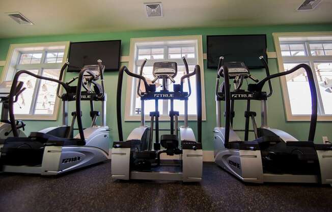 Three treadmills are lined up in a row in a room.