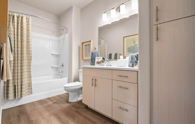 A bathroom with a toilet, sink, and cabinets.
