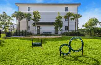 a white building with palm trees and a green lawn with a sign in the grass