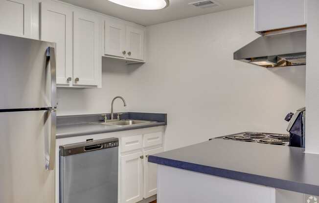 an empty kitchen with white cabinets and a stainless steel refrigerator