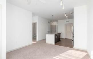 A white kitchen with a white island in the middle of a white room.