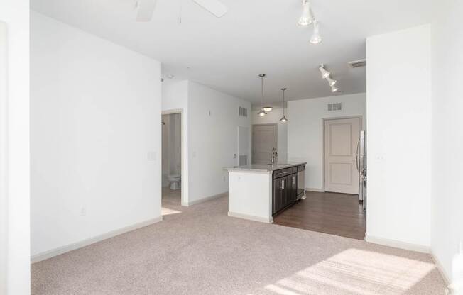 A white kitchen with a white island in the middle of a white room.