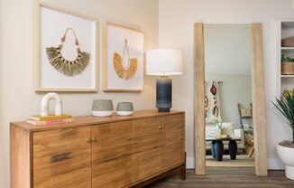 a living room with a dresser and three wall hangings