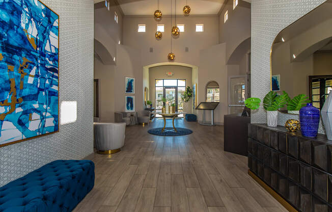 A large blue and gold abstract painting hangs on a white wall in a spacious lobby.