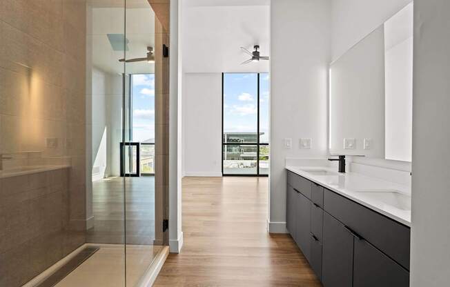 A modern bathroom with a walk-in shower and a view of the outdoors.