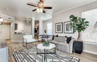 A living room with a white couch, a black and white rug, and a ceiling fan.