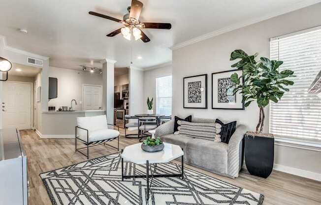 A living room with a white couch, a black and white rug, and a ceiling fan.