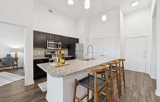A kitchen with a granite countertop and bar stools.