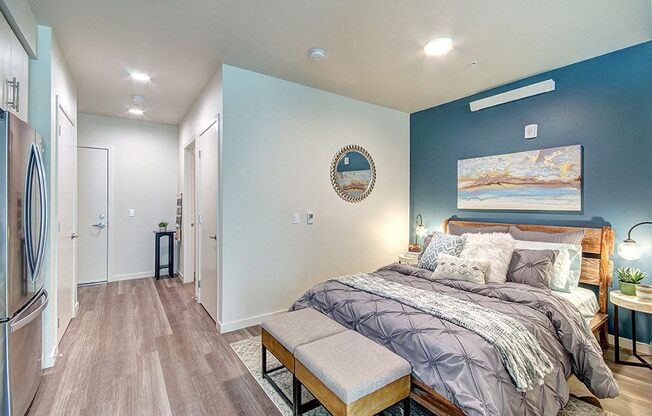 A bedroom with a bed, bench, and a painting on the wall. at Ravello Apartments, Washington