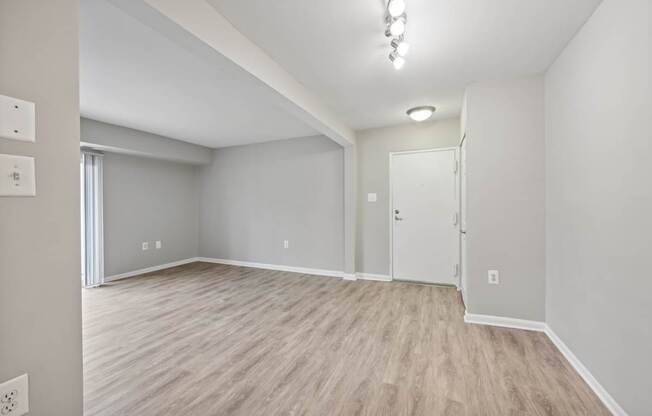 an empty living room with white walls and wood flooring at ReNew Odenton