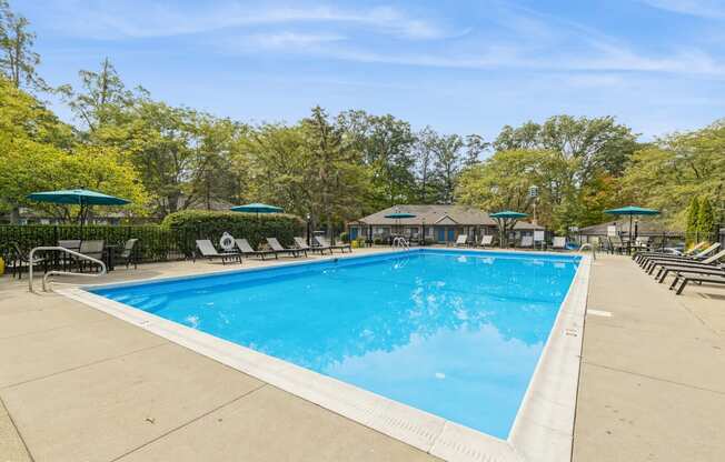a swimming pool with chairs and umbrellas at the resort on a sunny day