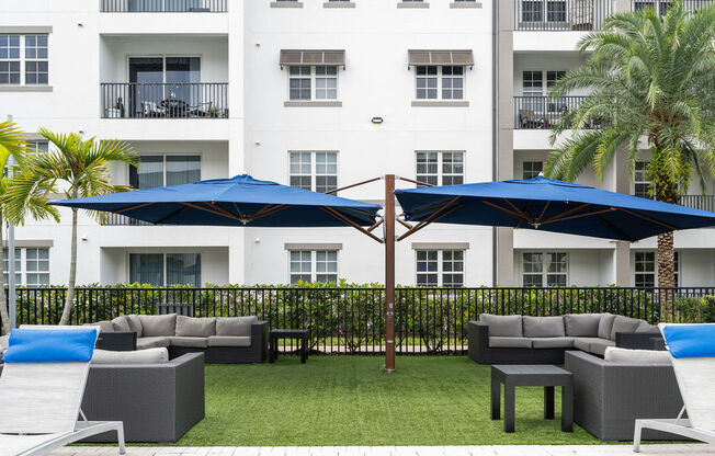 a patio with couches and umbrellas in front of a building