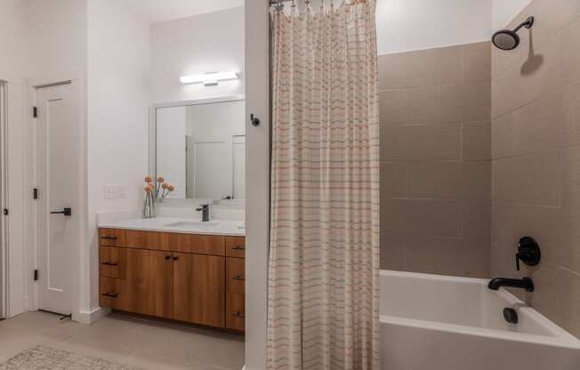 One-Bedroom Apartments in Old East Dallas, TX - 4600 Ross - Bathroom with Wood Cabinets, White Counters, a Shower with a Tub, and Tile Flooring