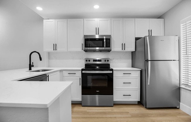 A modern kitchen with white cabinets and stainless steel appliances.