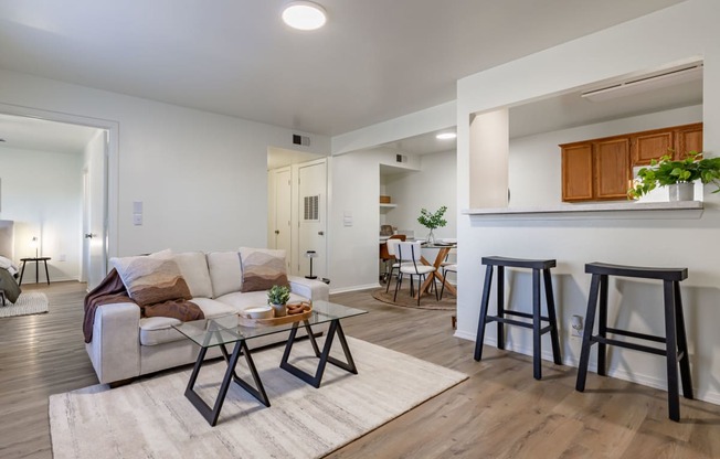 a living room with a couch and stools in front of a kitchen