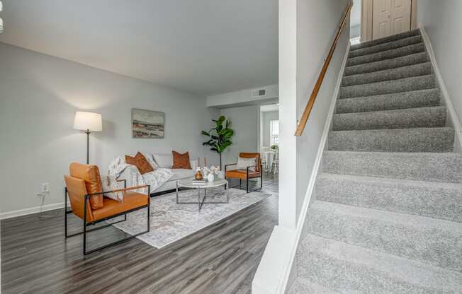 a living room with a staircase and a couch and chairs