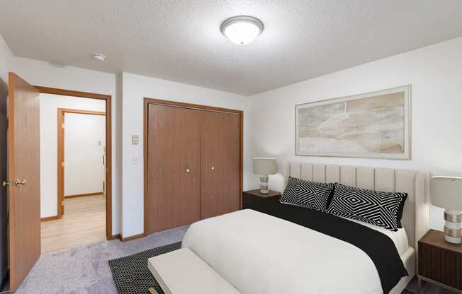 a bedroom with a bed and a closet and a door to a bathroom. Fargo, ND Flagstone Apartments