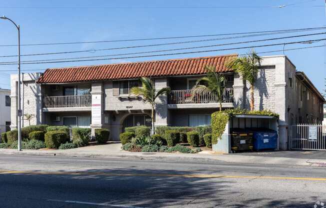 A building with a red tile roof and a blue dumpster in front.