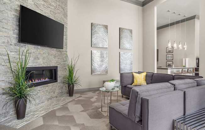A modern living room with a stone fireplace and grey couches.