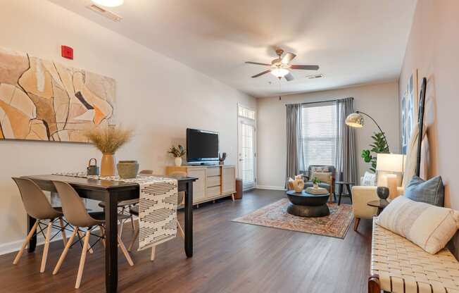 a living room with a dining room table and a ceiling fan