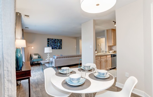 a dining area with a table and chairs and a kitchen in the background