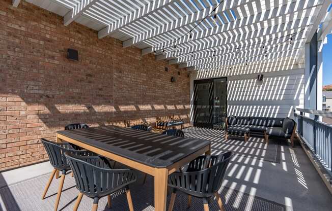 a patio with a wooden table and chairs and a brick wall