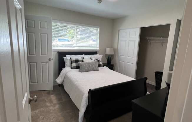 A bedroom with a bed, nightstand, and lamp.